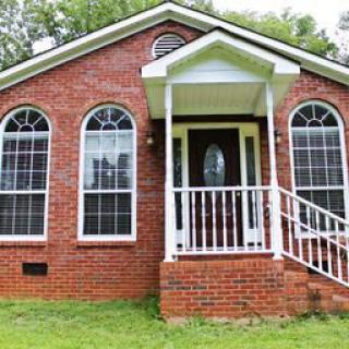 A brick house with large arched windows and a small front porch.