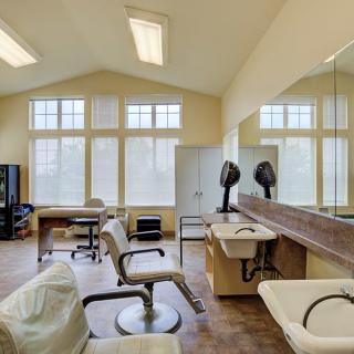 A bright and spacious hair salon with styling chairs, mirrors, and large windows.