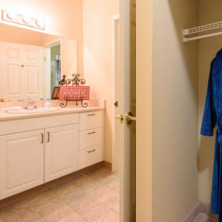 A bathroom with a vanity and a nearby closet featuring a blue robe.