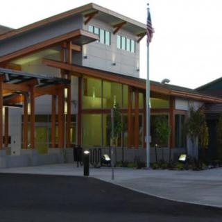 A modern building with wood accents, illuminated in the evening.