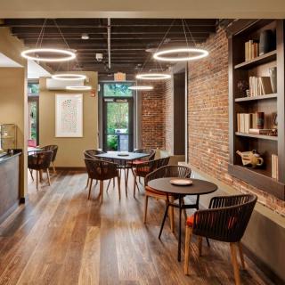 A modern cafe interior with cozy seating, brick walls, and circular lighting.