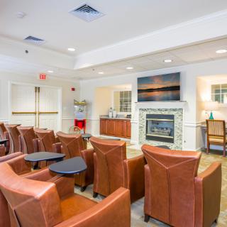 A modern lounge area featuring leather armchairs, a fireplace, and a television.