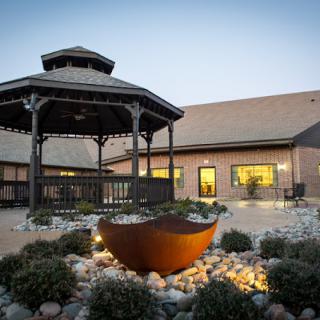 A well-lit gazebo in a garden setting during the evening.
