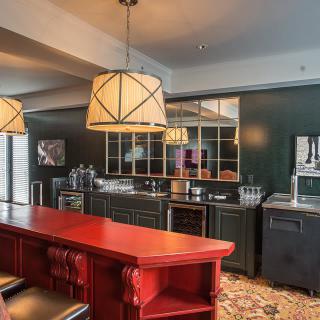 A modern kitchen with a bar area, featuring a red countertop and pendant lighting.