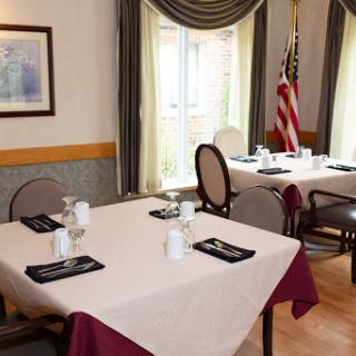A dining area set up for guests, featuring neatly arranged tables and an American flag.