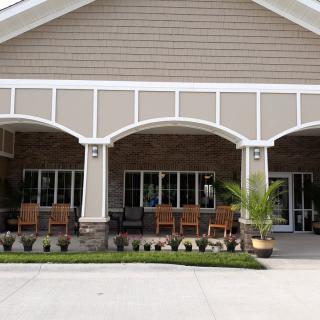 A building with a large porch featuring several chairs and potted plants.