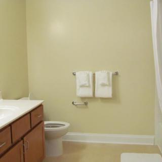 A clean and simple bathroom with a toilet, sink, and towels hanging on the wall.