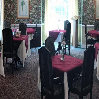 An elegant dining area with neatly arranged tables and chairs, featuring red tablecloths.