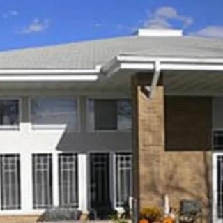 A modern house with large windows and a sleek roof design.