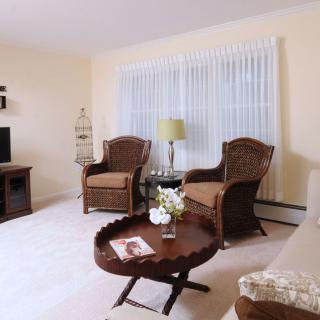 A cozy living room featuring rattan chairs, a round coffee table, and a TV stand with warm lighting.