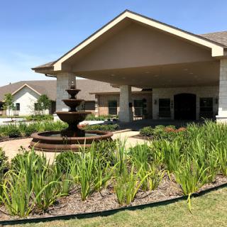 A beautifully landscaped entrance featuring a fountain and well-maintained gardens.