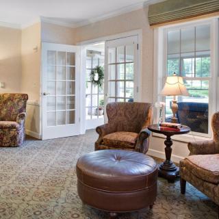 A cozy living room with armchairs, an ottoman, and a warm ambiance.