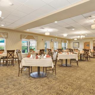 A well-lit dining room with neatly arranged tables and chairs, featuring elegant decor.