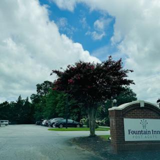 Entrance to Fountain Inn surrounded by greenery and a cloudy sky.