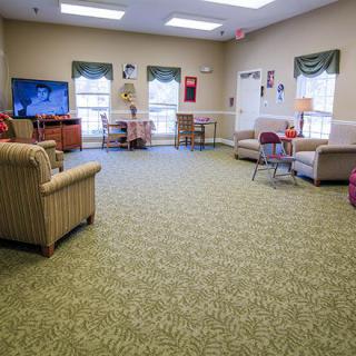 A spacious living room with comfortable seating, a television, and large windows.