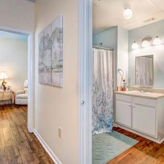 A view of a cozy bathroom with a hallway leading to a well-lit living area.