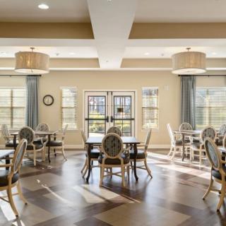 A spacious dining room with elegant decor, featuring multiple tables and chairs under soft ceiling lights.