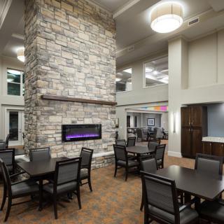 A modern dining area with a central stone fireplace and multiple tables and chairs.