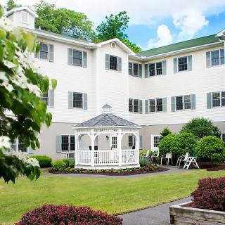 A well-maintained courtyard featuring a white gazebo surrounded by lush greenery and a multi-story residential building.