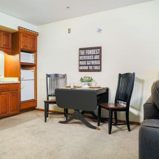 A cozy dining space with a small table and chairs adjacent to a kitchen with wooden cabinets.