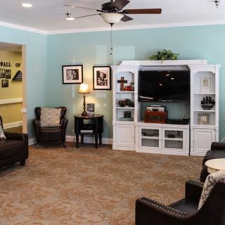 A cozy living room with blue walls, featuring a white entertainment cabinet and comfortable leather chairs.