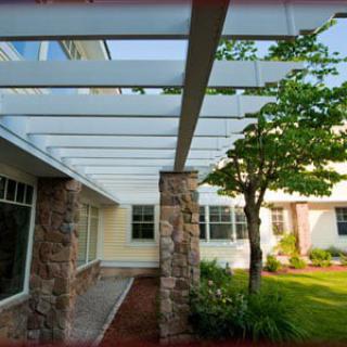 A beautiful outdoor space featuring a pergola with stone columns, surrounded by a well-maintained garden.