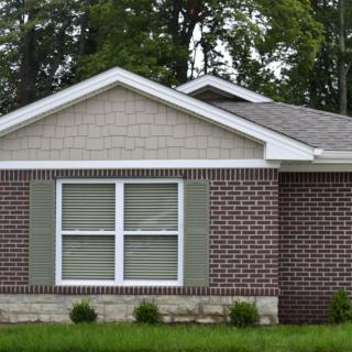 A suburban brick house with a gabled roof and large windows.