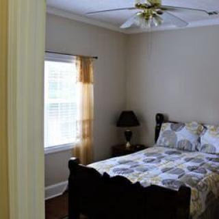 A cozy bedroom with a bed, window, and ceiling fan.