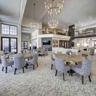 A spacious and elegantly designed dining area featuring modern furniture and large chandeliers.