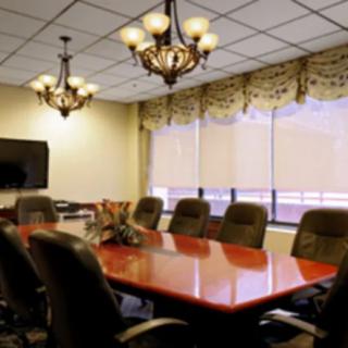 A conference room with a large table, surrounded by chairs and lit by chandeliers.