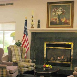 A cozy living room with a fireplace, armchairs, and an American flag.