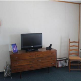 A simple room setup with a wooden dresser, television, and chair.