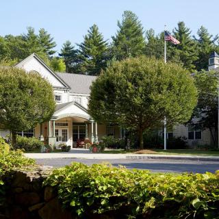 A scenic view of a building surrounded by lush greenery and trees, with a clear blue sky above.