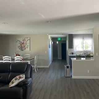 A modern open-concept living and dining area with a view into the kitchen. The room features wood flooring, a leather couch, and a dining table with chairs.
