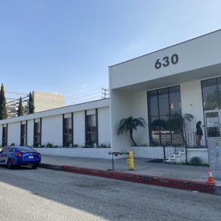 A modern commercial building with a blue car parked outside, featuring the number 630 on its facade.
