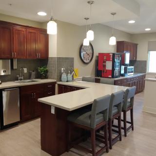 A modern kitchen interior with wooden cabinets, a large island countertop, and stylish hanging lights.