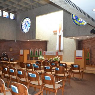 Interior of a church with pews and stained glass windows.