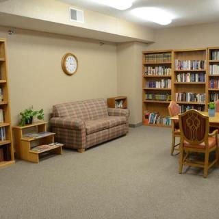 A cozy reading room with bookshelves, a sofa, and a table with chairs.