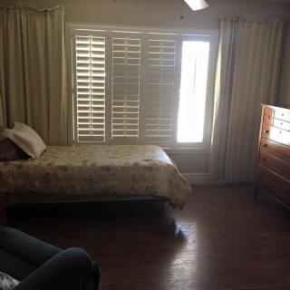 A cozy bedroom with a bed, curtains, and wooden flooring.