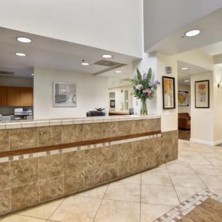 A modern office lobby with a tiled reception desk and decorative artwork on the walls.