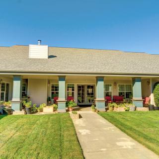 A single-story house with a well-maintained front lawn and a spacious porch.
