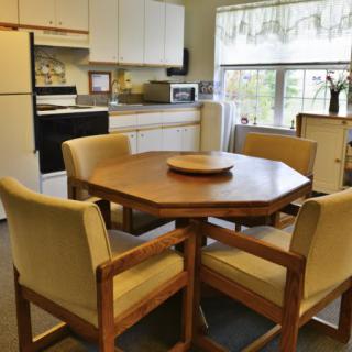 A cozy kitchen with a wooden dining table and upholstered chairs.