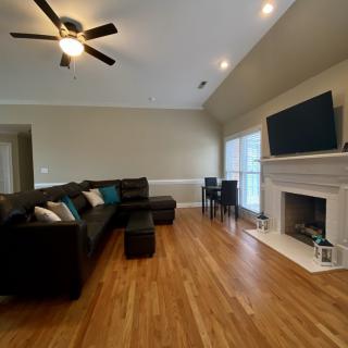 A cozy living room featuring a large sectional sofa, hardwood flooring, and a fireplace with a mounted television.