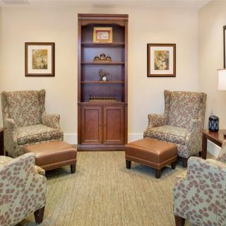 A cozy living room with patterned armchairs and a wooden bookshelf.