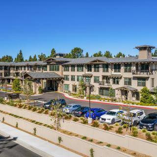 A modern three-story building with a parking lot and landscaped surroundings.