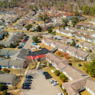 Aerial view of a suburban neighborhood showcasing rows of houses and a nearby parking lot.