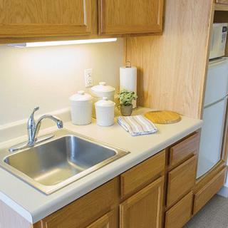 A clean kitchen with wooden cabinets and a stainless steel sink.