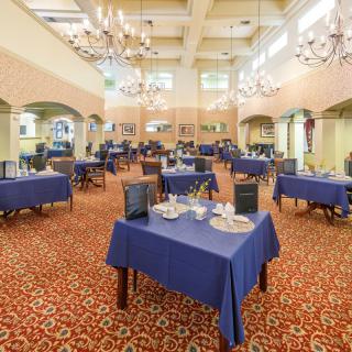 An elegantly designed banquet hall with blue tablecloths and chandeliers.