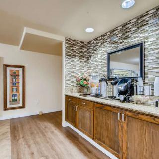 A modern kitchenette featuring a coffee station with wooden cabinets and stylish decor.