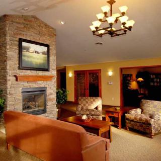 A cozy living room with a stone fireplace, comfortable seating, and warm lighting.